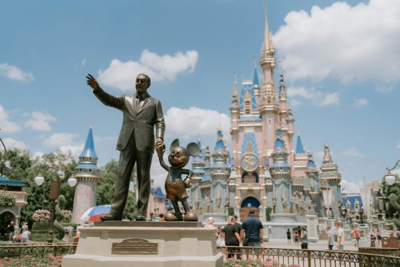 Estatua de Walt Disney y Mickey Mouse enfrente del castillo de Disneyland.