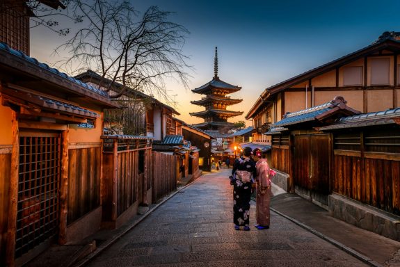 Paseo tranquilo con casas tradicionales y una pagoda al atardecer en Japón.